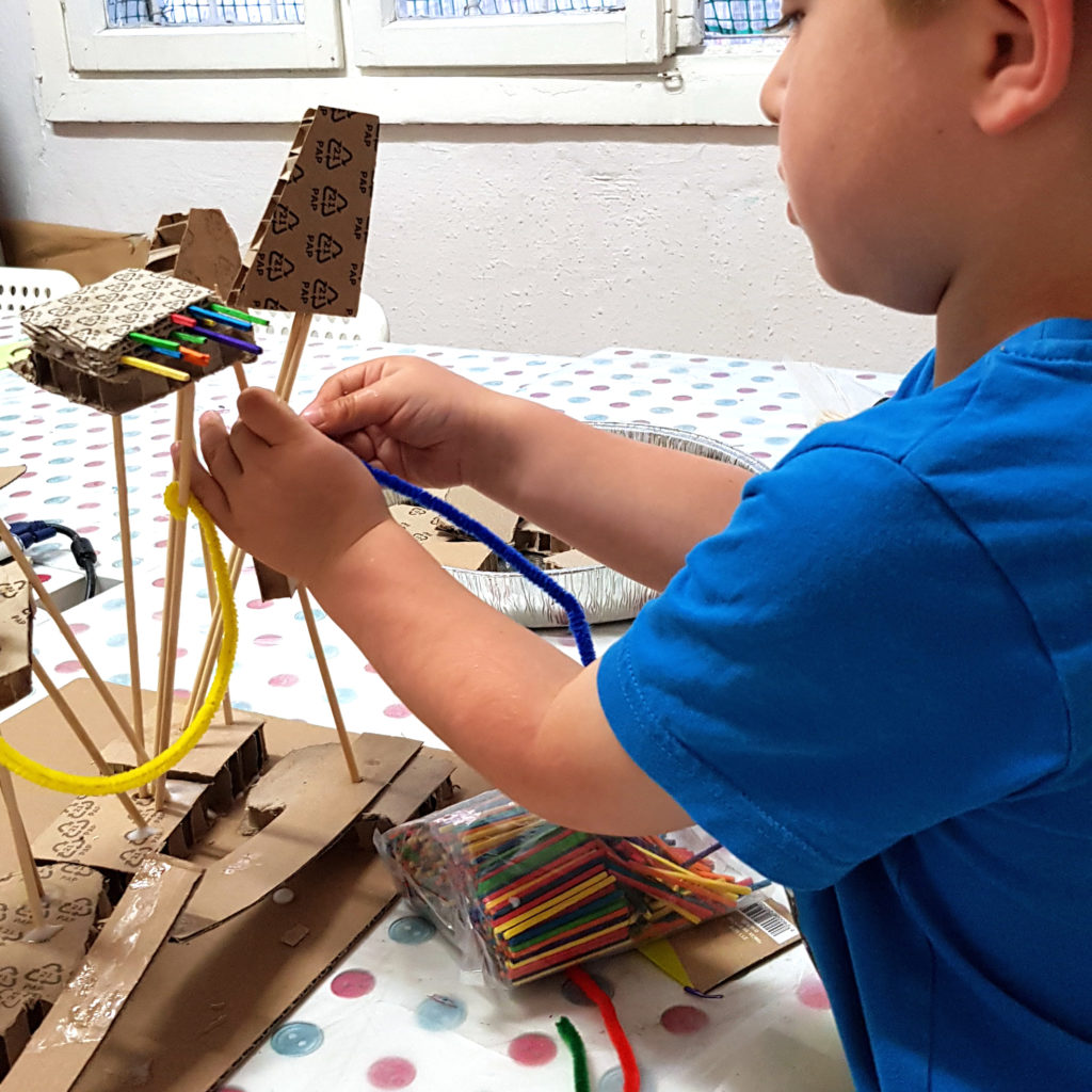 маленький ребенок строит макет из картона