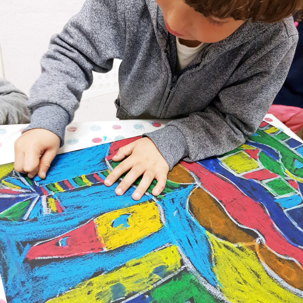 ребенок рисует пейзаж масляной пастелью на черном фоне